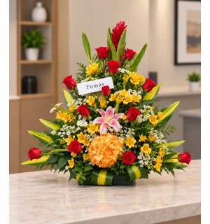 Arreglo floral Felicidades con rosas rojas, lilium rosado, astromelias amarillas y follajes sobre una mesa